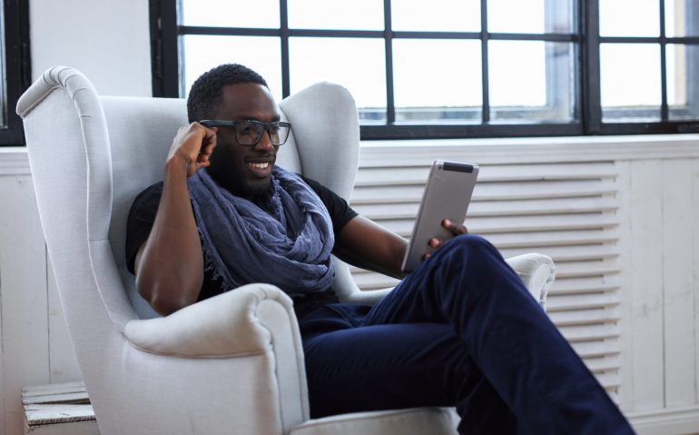 Blackman in eyeglasses working with table pc.