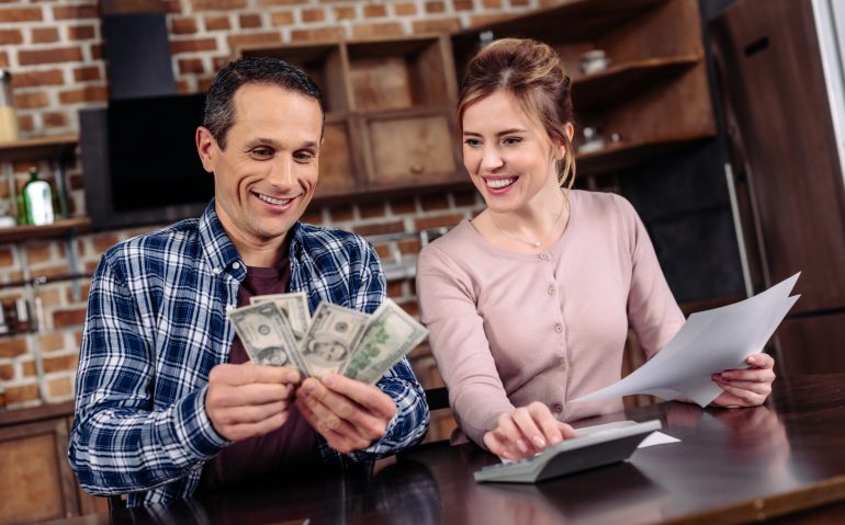 portrait of happy couple counting money together at home